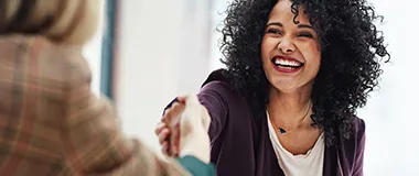 a woman smiling while hand shaking